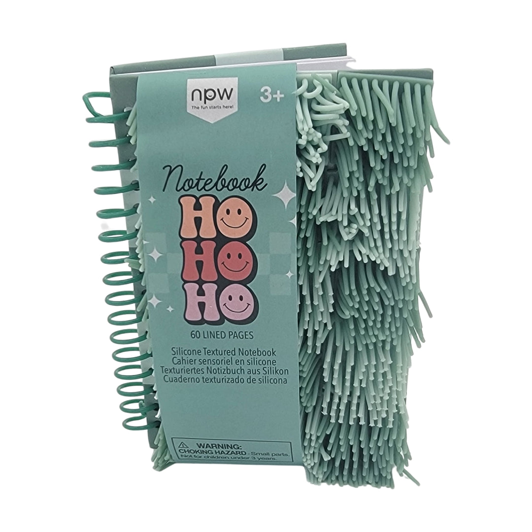 The "Ho Ho Ho" notebook features a green silicone-textured cover adorned with smiley faces, spiral binding, and contains 60 lined pages. It is suitable for ages 3 and up.