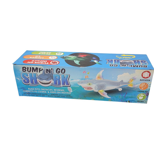 Box of the "Bump n go shark" toy, adorned with a playful shark illustration. Ensures continuous movement and obstacle avoidance while being designed to light up and rotate.