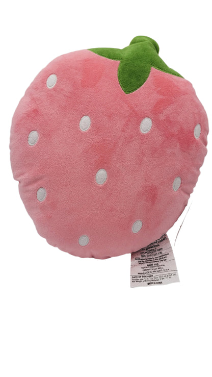 A strawberry-shaped decorative pillow is designed with pink fabric, adorned with white polka dots and topped with green leaves.