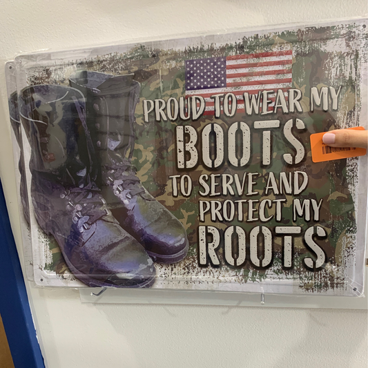 The Patriotic metal sign features boots, a U.S. flag, and a camo background with the phrase "Proud to wear my boots to serve and protect my roots.