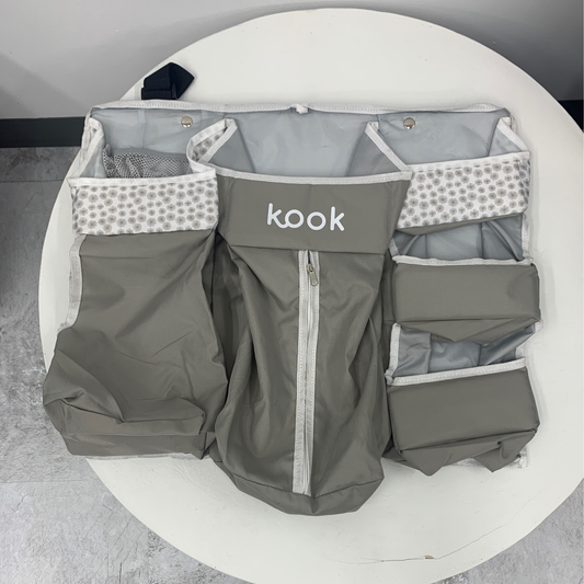 A gray fabric Kook Organizer with multiple pockets, displayed on a white table.