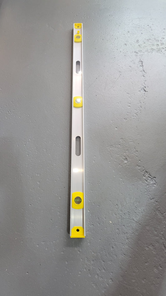 A 48" level with yellow accents and multiple bubble vials lies on a gray concrete surface.