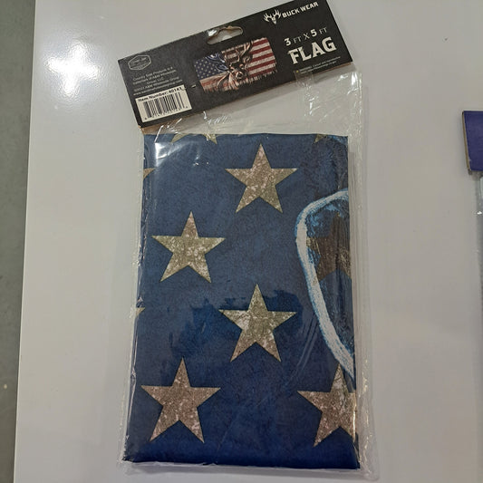 A blue 3'x5' packaged USA Flag with partly visible white stars. The label reads "Buck Wear 3 ft. x 5 ft. Flag.