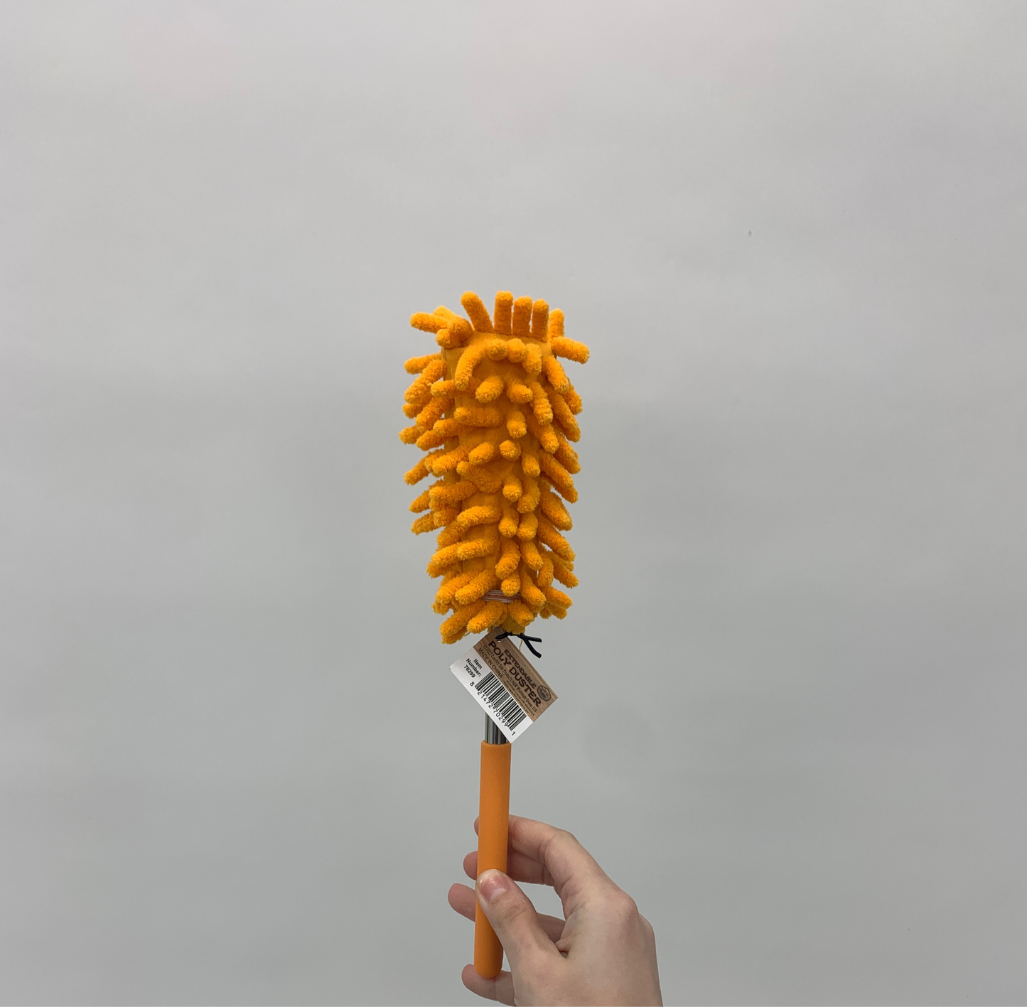 Hand holding an extendable poly duster with a microfiber head against a plain white background.