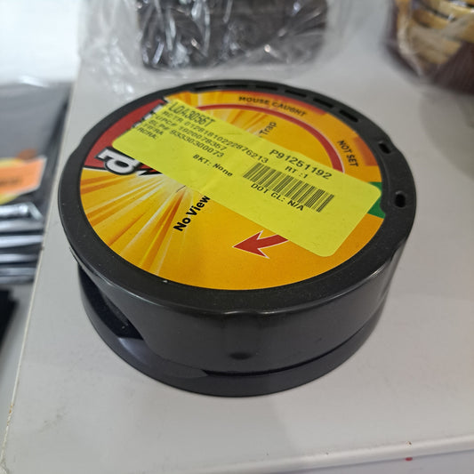 A black plastic pest control trap with a yellow label and barcode sits on a white surface.