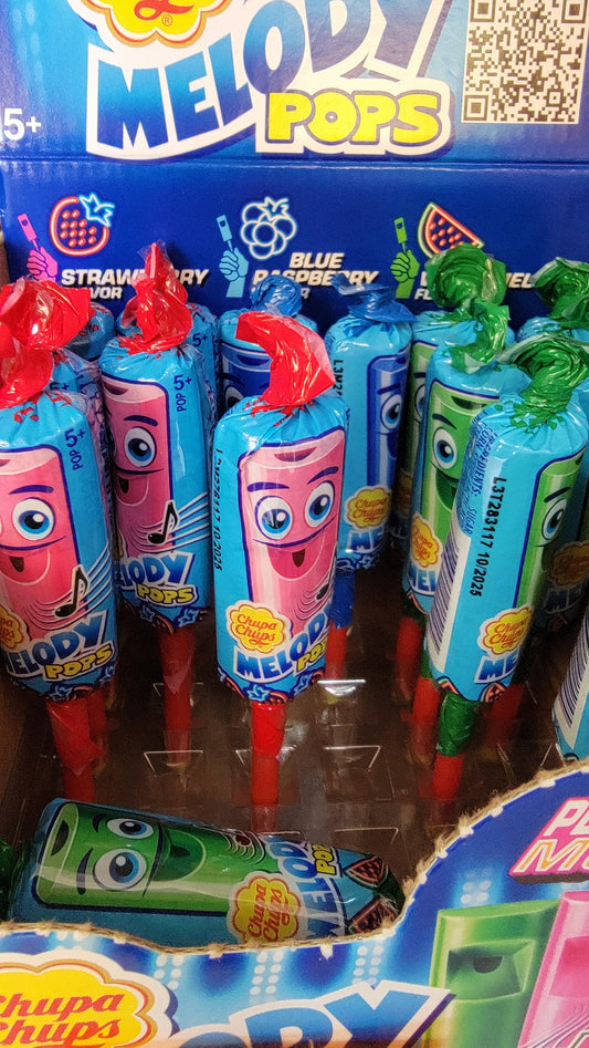 A display of Melody Whistle Pops featuring strawberry, blue raspberry, and apple flavors. The lollipops come wrapped in colorful packaging adorned with cartoon characters and text promoting the product.