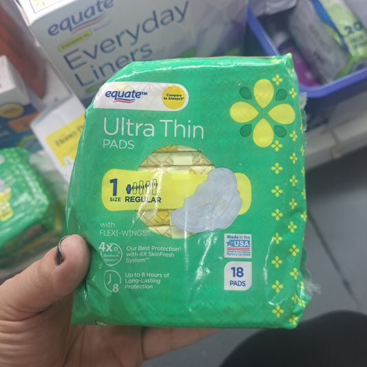 A hand holds a package of Hygiene Pads/Tampons, size 1 regular, with 18 pads. The green packaging highlights 4x skin protection and up to 8 hours of protection.