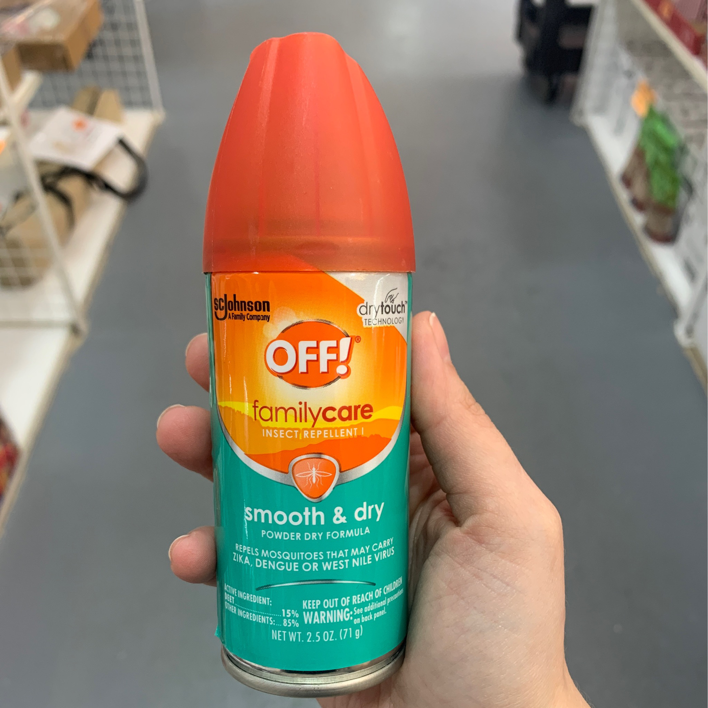 Hand holding a can of Off insect repellent 2.5 oz in a store aisle.