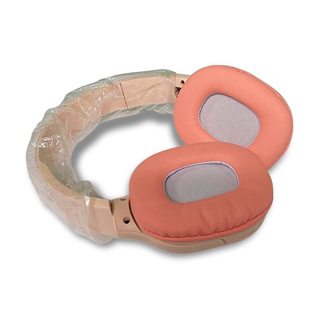 Peach-colored HN06 Wireless Headphones, featuring plastic wrapping on the headband, rest on a white surface. Equipped with wireless version 5.3 technology, they provide a frequency response of 20-2000 Hz and allow up to 40 hours of uninterrupted music play time.