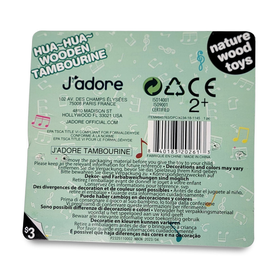 The back of the J' adore wooden Tambourine toy features brand details, safety certifications, an age recommendation of 2+, and a price of $3, with a design including musical notes and pastel colors.