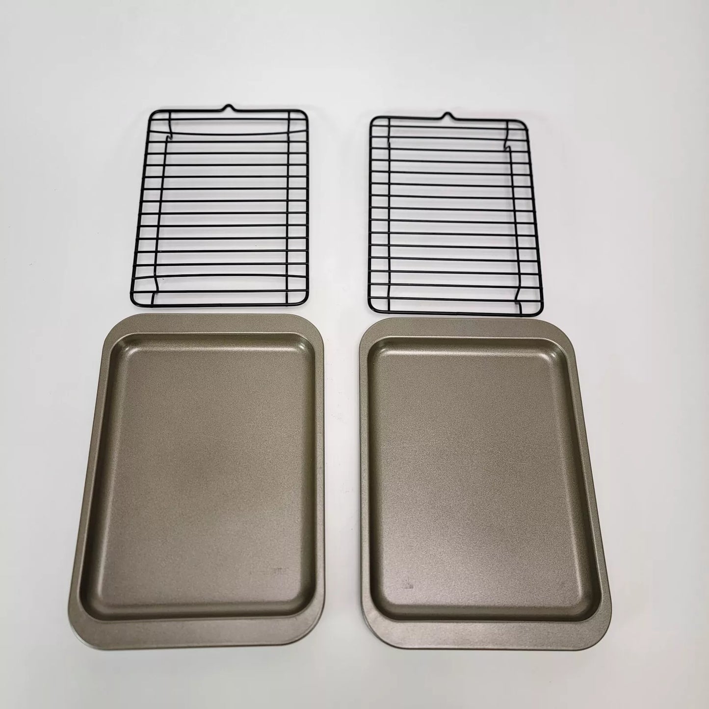 A set of two Roast & Broiler Pans and two black cooling racks on a white surface.