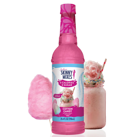 A bottle of Jordan's Skinny Syrup Cotton Candy, Sugar Free, 25.4oz is displayed alongside a cotton candy stick and a pink milkshake adorned with whipped cream and sprinkles.